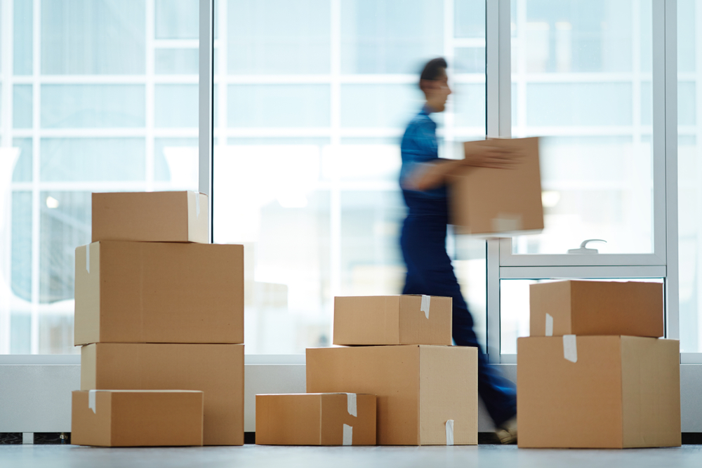 man walking by packed boxes while carrying a box ready for commercial moving